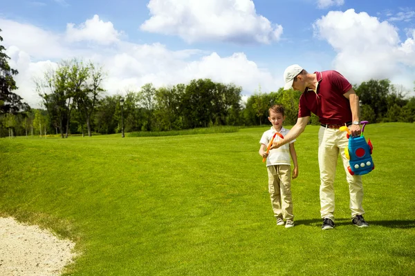 Padre con hijo están entrenando en el campo de golf — Foto de Stock