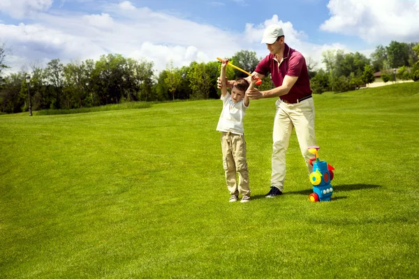 Батько з сином тренується на полі для гольфу — стокове фото