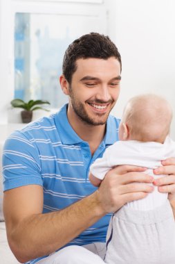 bir bebekle oynarken mutlu baba