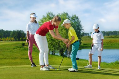 Eğitmen çocuklarla golf okulda çalışıyor.