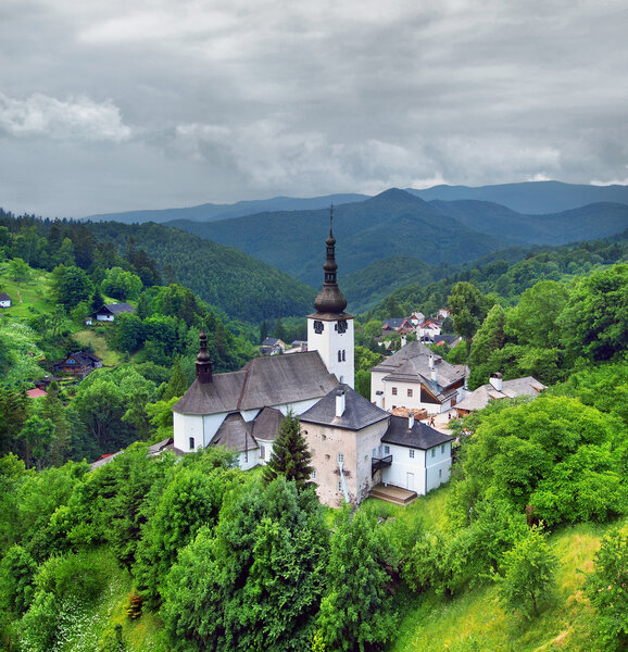 The church of the Transfiguration in the village of Spania Dolina surrounded by the Stare Hory and Velka Fatra mountains in central Slovakia. The Spania Dolina is a historical mining village and one of the top tourist destinations in Slovakia.