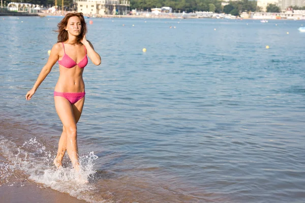 Fille aux cheveux bruns en maillot de bain marchant sur la plage — Photo