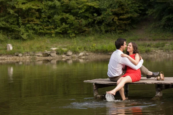 Un par de personas enamoradas se sientan en el puente —  Fotos de Stock