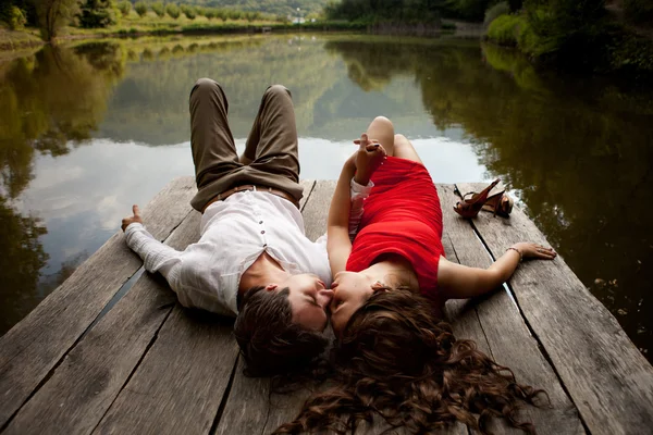 Man and woman are looking at each other on a wooden bridge over — Stock Photo, Image