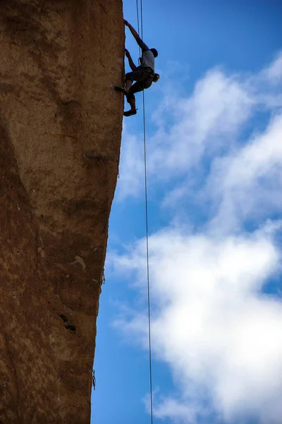 Climber dwarfed by the overhanging  cliff of Monkey Face, Smith Rock State Park, Central Oregon