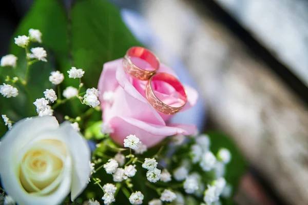 Wedding rings and bouquet on the table — Stock Photo, Image