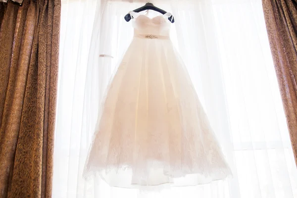 Wedding dress hanging on the chandelier in the room — Stock Photo, Image