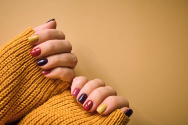 Sonbahar renklerinde manikür, sıcak yün kazaklı kadın elleri. Moda Sonbahar Kış Tırnak Tasarımı.