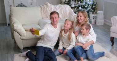 Kafkasyalı bir aile, arkadaşlarıyla Noel 'i kutlamak için akıllı telefon kullanıyor. Aile, Noel arifesinde internette akrabalarınızı selamlar..