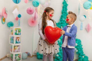 Kırmızı kalp balonu olan iki sevimli çocuk. Sevgililer Günü ve aşk konsepti, stüdyo çekimi.