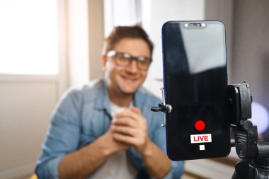 Ellerim serbest. Akıllı telefon tripoda takılmadan önce orta yaşlı bir erkek evde oturuyor. Video blogcusu içeriği kanala kaydediyor. Genç adam video akışı yapıyor