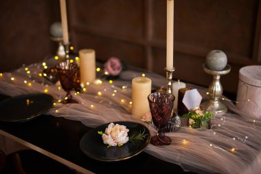 Romantik ya da düğün yemeği ya da tatil sofrası, kahverengi, pembe ve altın renkli mumlar ve çelenk süslemesi. Ayrıntıları kapat, seçici odaklanma
