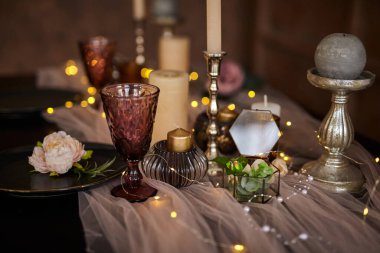 Romantik ya da düğün yemeği ya da tatil sofrası, kahverengi, pembe ve altın renkli mumlar ve çelenk süslemesi. Ayrıntıları kapat, seçici odaklanma