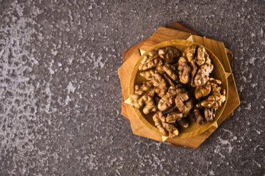 Siyah arka planda ahşap kasede ceviz ve fotokopi alanı. Üst Manzara. Siyah arka planda soyulmuş ceviz kaplı ahşap bir tabak. Metin için boşluk