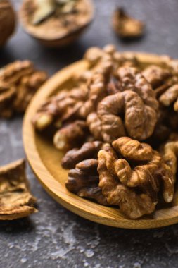Siyah arka planda ahşap kasede ceviz ve fotokopi alanı. Üst Manzara. Siyah arka planda soyulmuş ceviz kaplı ahşap bir tabak. Metin için boşluk