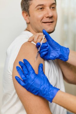 Doktorun elini kapat Coronavirus Covid 'e karşı aşı yap. 19 yaşında, klinikteki genç bir adama.