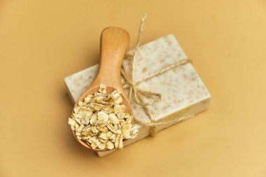 Bej arka planda el yapımı doğal banyo yulaf spa sabunu. Tahta bir kasede sabun ve yulaf ezmesi. Sabun kalıpları. Spa, deri ve vücut bakımı. Hediye paketi.