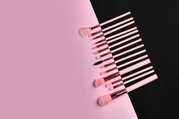 Set of professional brushes on a black and pink colored composed background top view point flat lay with copy space for text