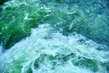 Bir şelaleden gelen dalgaların dalgaları yüksek gelgit ve alçak gelgit sırasında bir dağ nehrine akar. Suyun girdapları