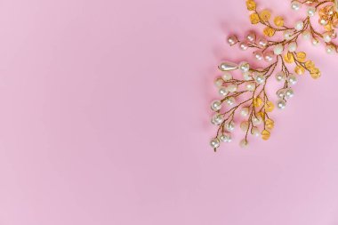 Beyaz ve sarı boncuklu el yapımı taraklar, fotokopi alanı ve pembe arka planı olan yakın plan. İnci ve boncuktan yapılmış saç süsü.