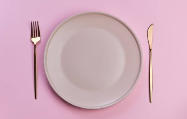 Pembe arka planda pembe tabak ve çatal bıçak takımı. Romantik bir akşam yemeği, Sevgililer Günü, yıldönümü ya da doğum günü için mükemmel. Uzayı kopyala Düz-yatay, üst görünüm.
