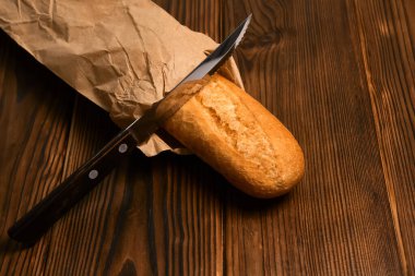 Kahverengi ahşap arka planda el yapımı ekmek bıçağında taze ekmek.