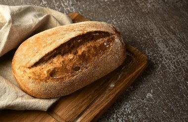 Gri arka planda kesme tahtasına tam tahıllı çavdar ekmeği. Seçici odak