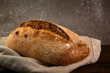 Gri arka planda kesme tahtasına tam tahıllı çavdar ekmeği. Seçici odak