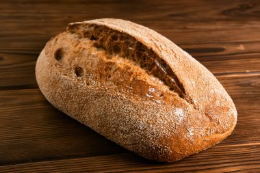 Kahverengi ahşap arka planda kesme tahtasının üzerinde tam tahıllı çavdar ekmeği. Seçici odak