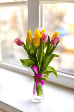 Beyaz pencere pervazında çok renkli laleler