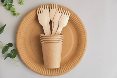 Gri arka planda yeşil yapraklı, çevre dostu kağıt sofra takımı. Geri dönüşüm konsepti. Üst Manzara. Uzayı kopyala Hiç atık teması.