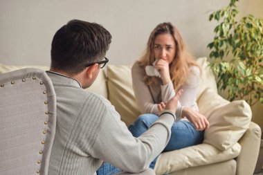 Heyecanlı ve üzgün hasta sorunları hakkında psikoterapisti dikkatle dinliyor. Psikologa giden kadın hasta.