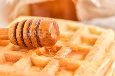 Taze Belçika waffle 'larının üzerine bal dökülüyor. Mineral ve vitamin açısından zengin organik sağlıklı kahvaltı. Kahvaltı için eko-yemek. Moda tatlı şekerlemeler