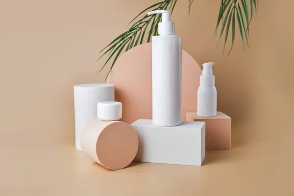 Trendy cosmetics tube and jar on pedestal at the beige background. Unbranded blank cosmetics packages. Skincare female products advertising mockup