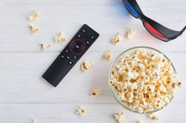 Bir kase patlamış mısır, 3D gözlükler, beyaz arka planda uzaktan kumanda. Boş zaman ve eğlence konsepti. Üst görünüm