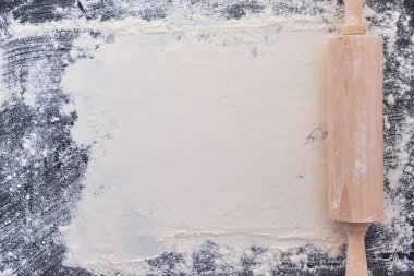 Tahta merdane ve unu kapatın. Siyah taş arka planda fırın. Üst Manzara. Metin için boş alan. Tarif için arkaplan