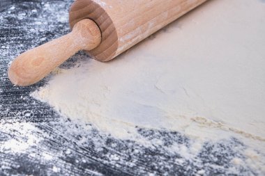 Tahta merdane ve unu kapatın. Siyah taş arka planda fırın. Üst Manzara. Metin için boş alan. Tarif için arkaplan