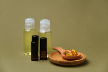 Yeşil arka plandaki tahta kaşıkta vitamin içeren kapsüller ve dizaynınız için bir kutu özüt, kopyalama alanı. Morina yağı kapsülleri masada. Sağlıklı yaşam tarzı kavramı.