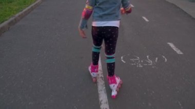 Koruyucu pedler takan ve kasklı küçük bir kız yaz parkında paten kaymayı öğreniyor. Çocuklar için açık hava sporu. Yavaş çekim