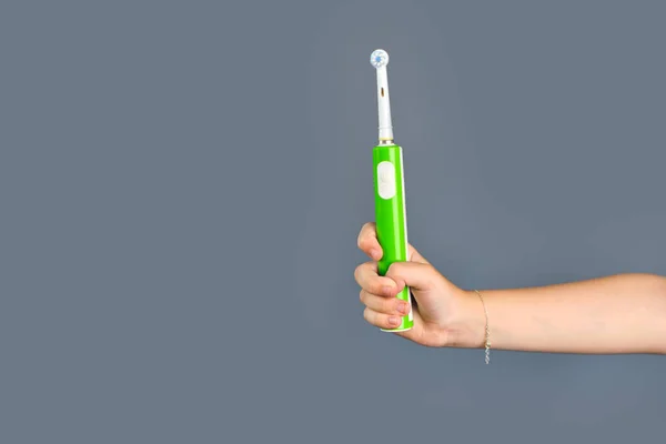 Χέρι Του Παιδιού Κρατά Μια Ηλεκτρική Οδοντόβουρτσα Απομονωμένη Γκρι Φόντο — Φωτογραφία Αρχείου