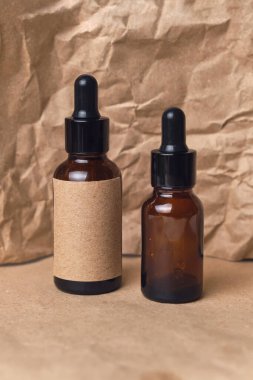 Kırışmış kağıtta iki kehribar rengi cam kahverengi damlacık şişesinde doğal aroma yağı. Organik güzellik ürünü ambalaj tasarımı
