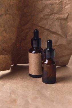 Kırışmış kağıtta iki kehribar rengi cam kahverengi damlacık şişesinde doğal aroma yağı. Organik güzellik ürünü ambalaj tasarımı