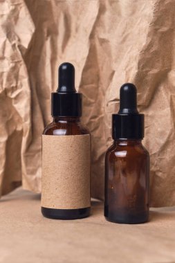 Kırışmış kağıtta iki kehribar rengi cam kahverengi damlacık şişesinde doğal aroma yağı. Organik güzellik ürünü ambalaj tasarımı