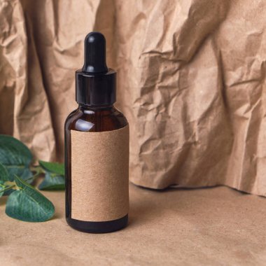 Kırışmış kağıtta kehribar rengi bir cam kahverengi damlacık şişesinde doğal aroma yağı. Organik güzellik ürünü ambalaj tasarımı