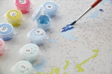 Tuvalin arka planında boyalı ve fırçalı numaralandırılmış kaplar var. Yaratıcı boş zaman aktiviteleri