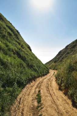 Mountain road through the canyon of green hills. Trail in hills. Travel concept