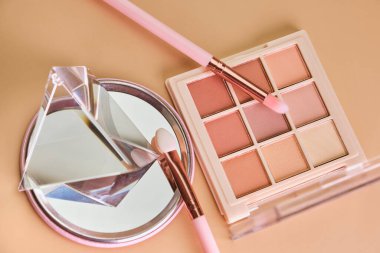Bej arka planda makyaj, ruj, ayna, far ve fırçalar için kozmetik ürünleri
