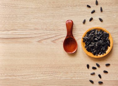 Ahşap tabakta ayçiçeği tohumlarının yakın çekimi ve fotokopi alanı olan köy masasında kaşık.