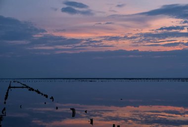 Renkli gökyüzü ve tuzlu göldeki renkli su günbatımında yansıyor.