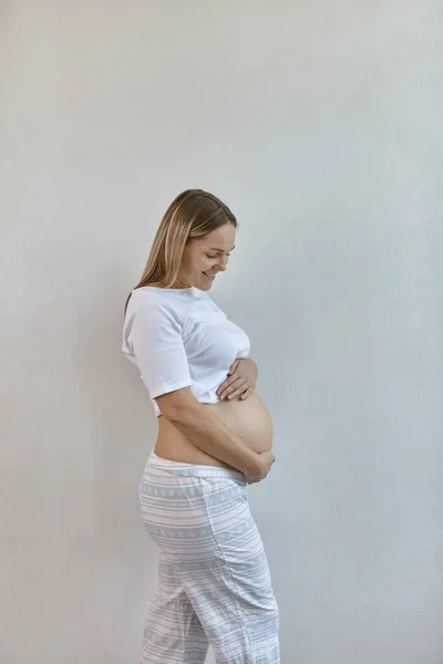 Bella Donna Incinta Pigiama Erge Sullo Sfondo Muro Bianco Casa — Foto Stock